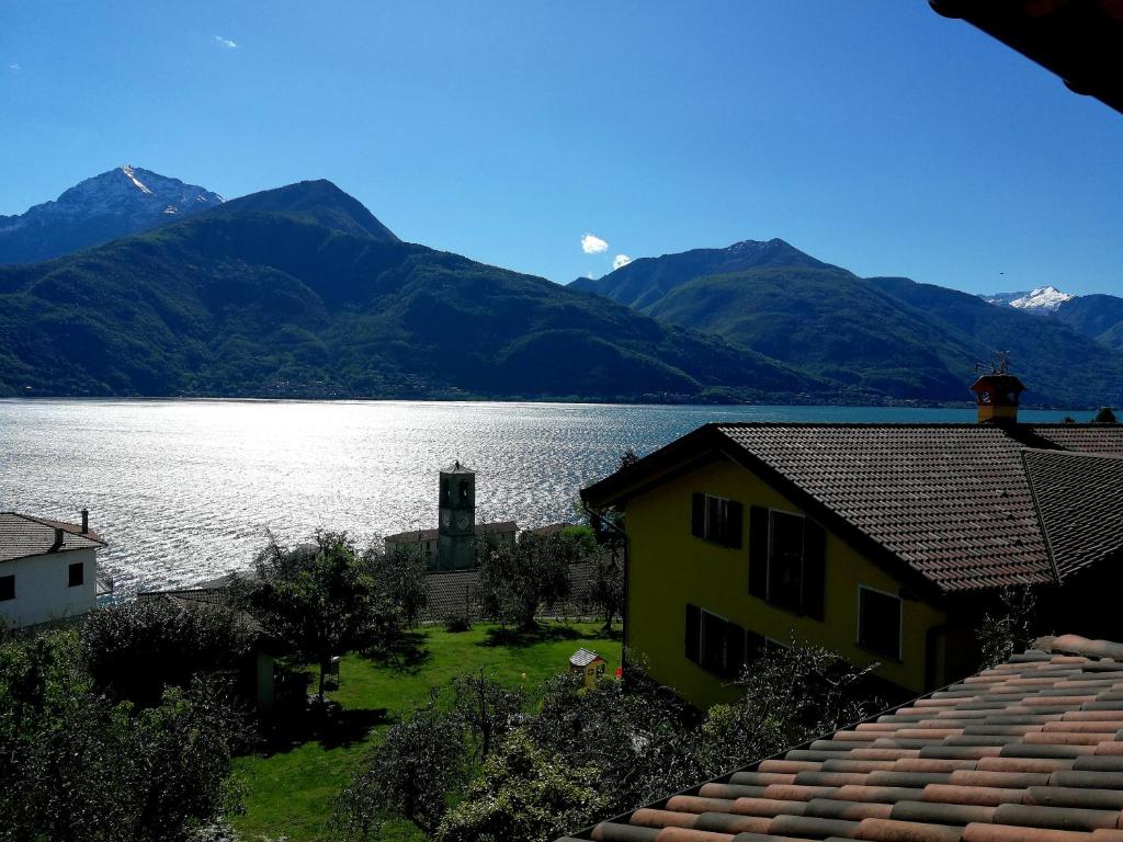 una casa amarilla junto a un lago con montañas en Appartamenti Il Medeghino, en Musso