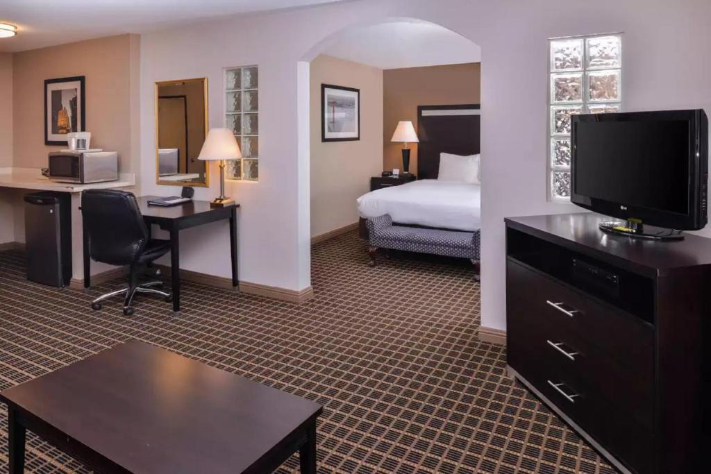 a hotel room with a bed and a desk with a television at Hotel Nova SFO in South San Francisco