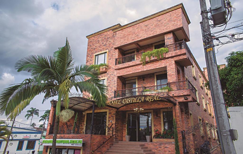 a brick building with a palm tree in front of it at Hotel Castilla Real in Pereira