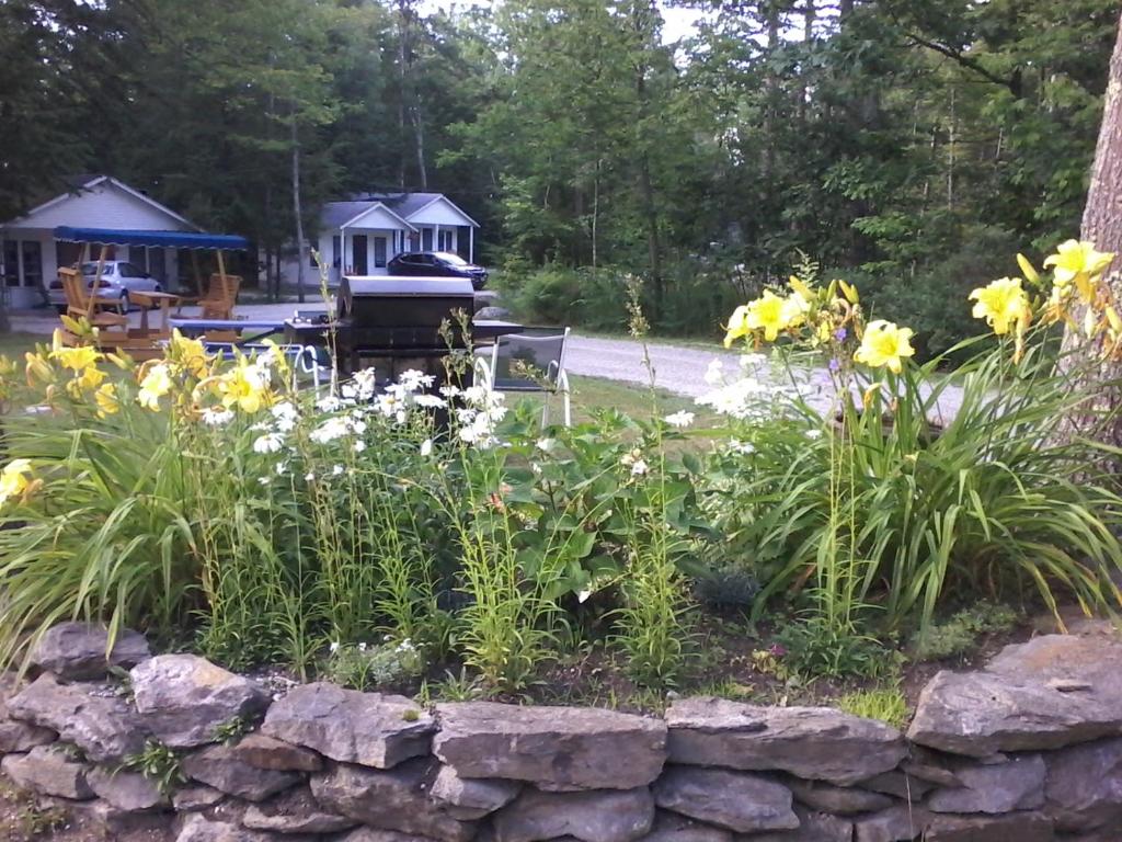 a garden with flowers and a stone wall at Maine Idyll Motor Court in Freeport