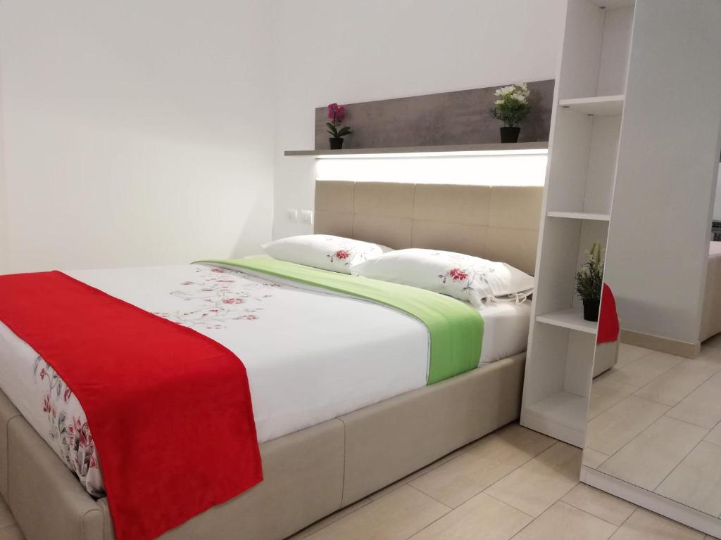 um quarto com uma cama com um cobertor vermelho e verde em Rogoredo Milan Apartments em Milão