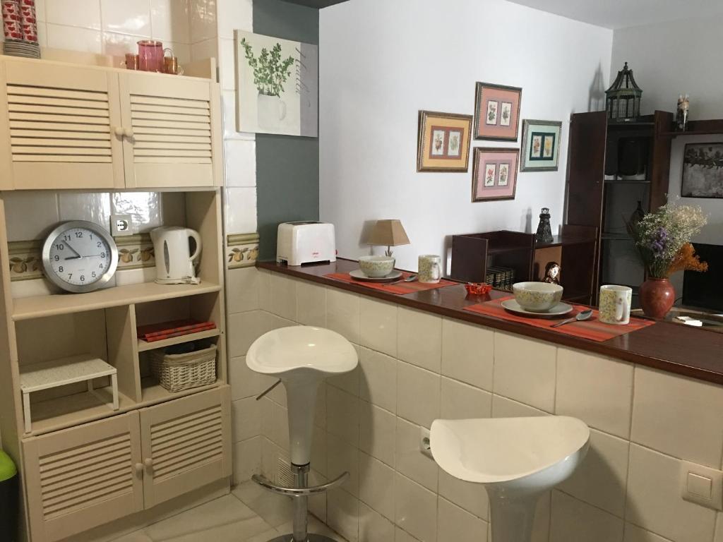 a kitchen with a counter with a clock and a stool at Apartamento Balneario playa Caleta in Cádiz