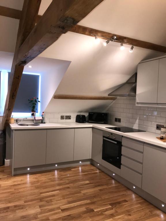 a kitchen with white cabinets and a wooden floor at Apartment 4, 1 Laura Place in Aberystwyth