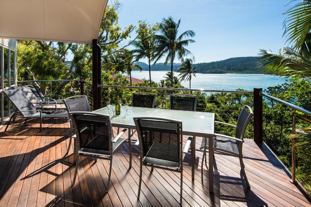 a table and chairs on a deck with a view of the ocean at Cooinda Gardens on Hamilton Island by HIHA in Hamilton Island