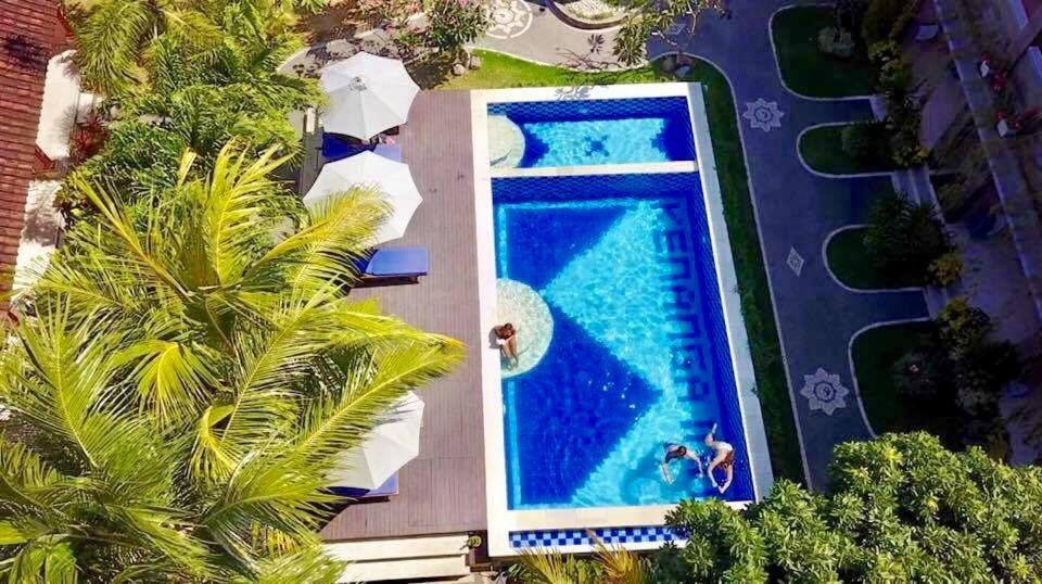 uma vista sobre uma piscina de resort com palmeiras em Kenanga Inn em Uluwatu