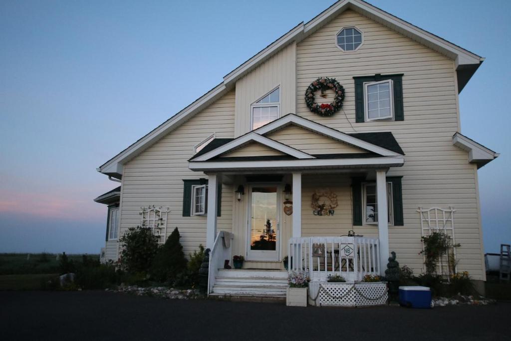 a white house with a wreath on the door at Phare des Dunes Lighthouse in Tracadie