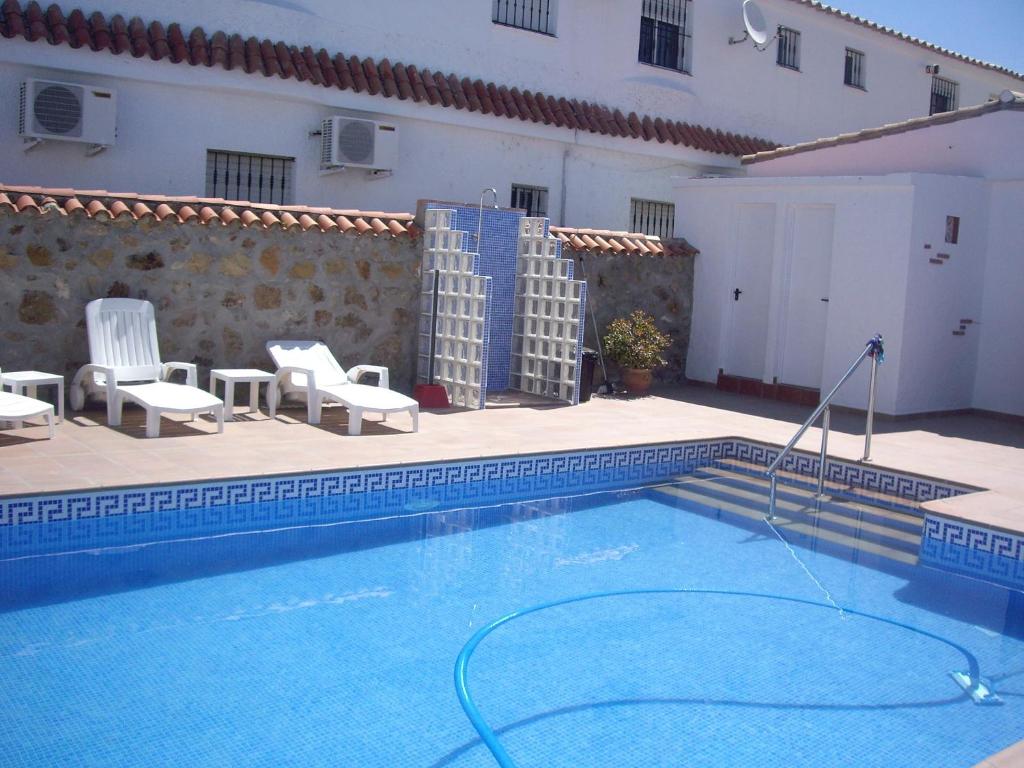 a swimming pool with chairs and a building at Hostal Mini Golf in Los Caños de Meca