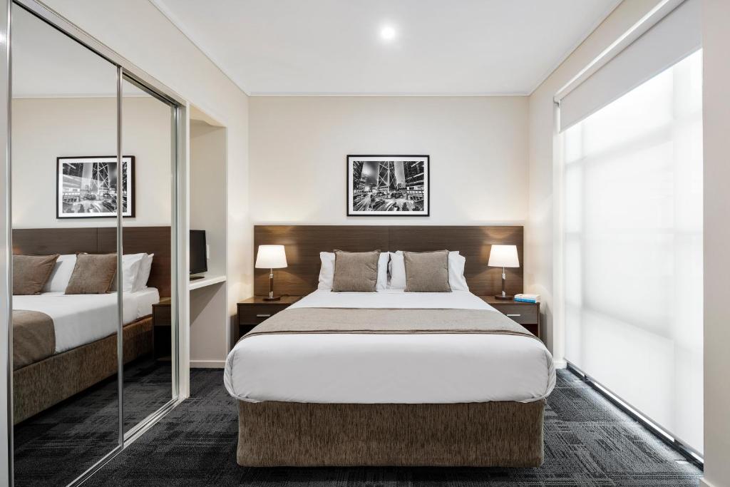 a hotel room with two beds and two lamps at Quest Narre Warren in Narre Warren