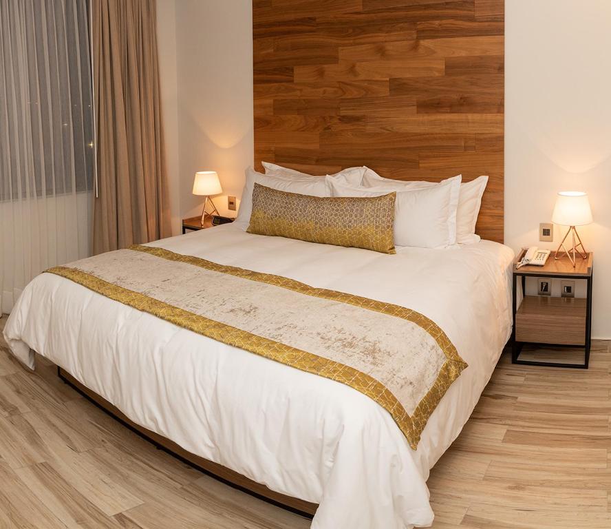 a bedroom with a large white bed with a wooden headboard at Hotel Verticca in Santa Cruz Tecamac