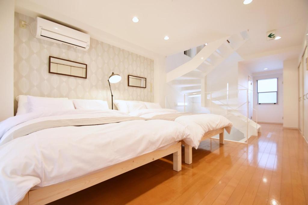 a white bedroom with four beds and a staircase at TERRACE HOUSE Shibuya Maruyamacho in Tokyo