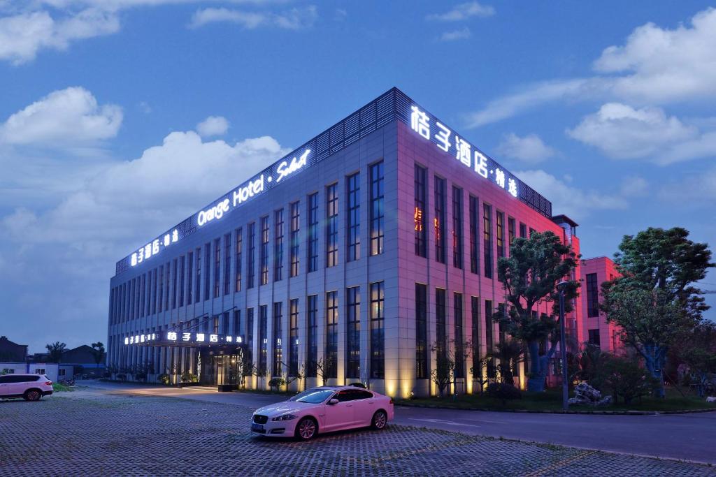 einem rosa Auto, das vor einem Gebäude parkt in der Unterkunft Orange hotel select (shanghai pudong Airport Hotel) in Shanghai