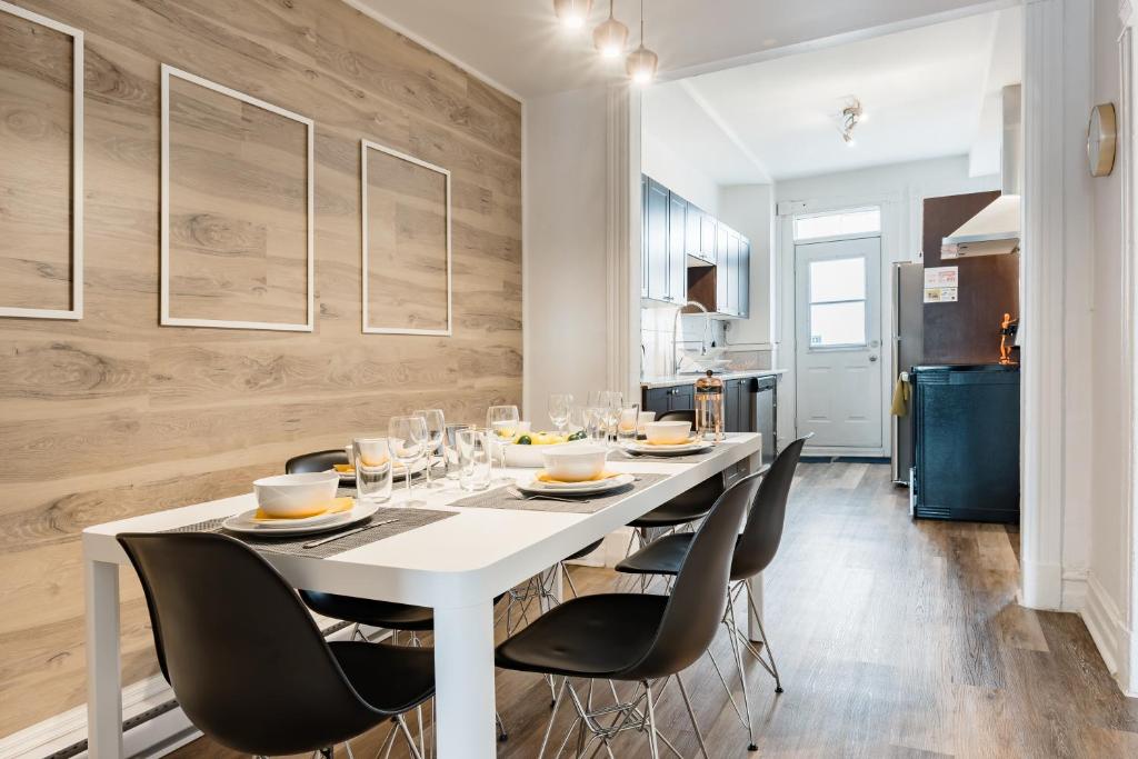 une salle à manger avec une table blanche et des chaises noires dans l'établissement Apartments Near Montreal Olympic Park, à Montréal