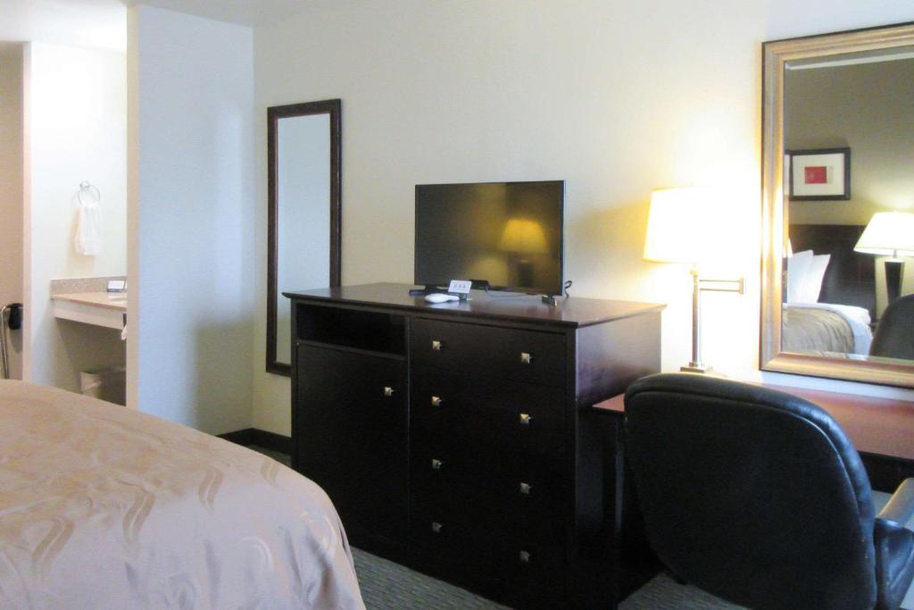 a hotel room with a bed and a dresser with a mirror at Quality Inn Longmont in Longmont