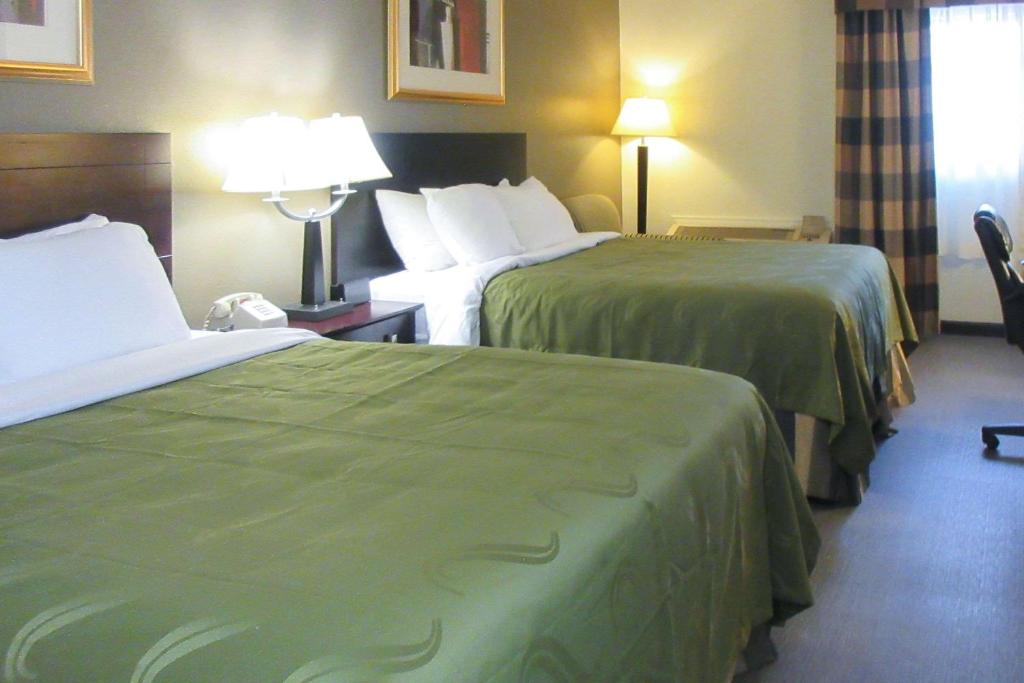 a hotel room with two beds with green sheets at Quality Inn Longmont in Longmont