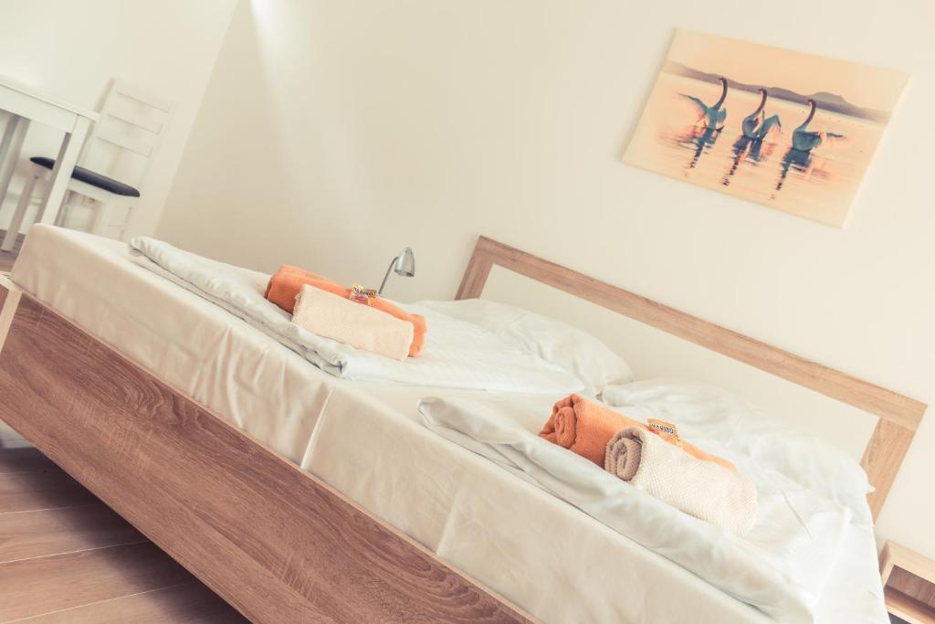 a bed with white sheets and two bags on it at Sekli Panzió in Balatonlelle