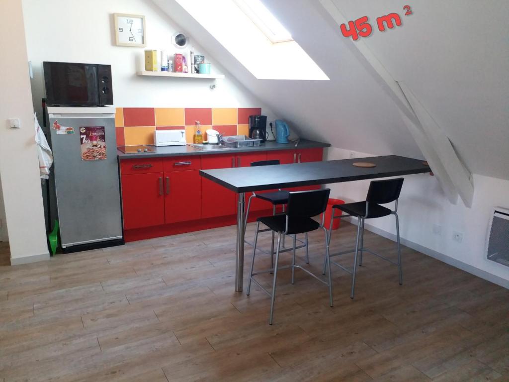 eine Küche mit roten Schränken sowie einem Tisch und Stühlen in der Unterkunft Appartements T2 Proche de Rennes in Chantepie