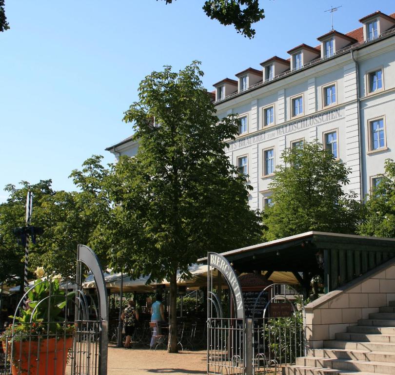 Hotel am Waldschlösschen - Brauhaus في درسدن: مبنى ابيض كبير امامه شجرة