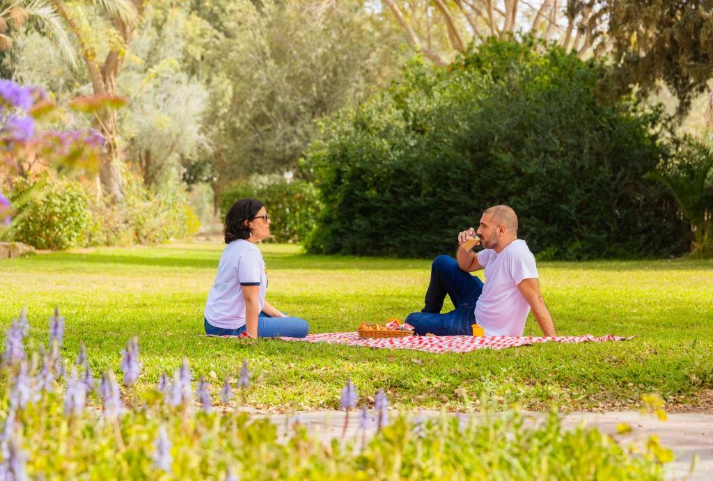 two people sitting on the grass in a park at Gvulot - Kibbutz experience in Gevulot