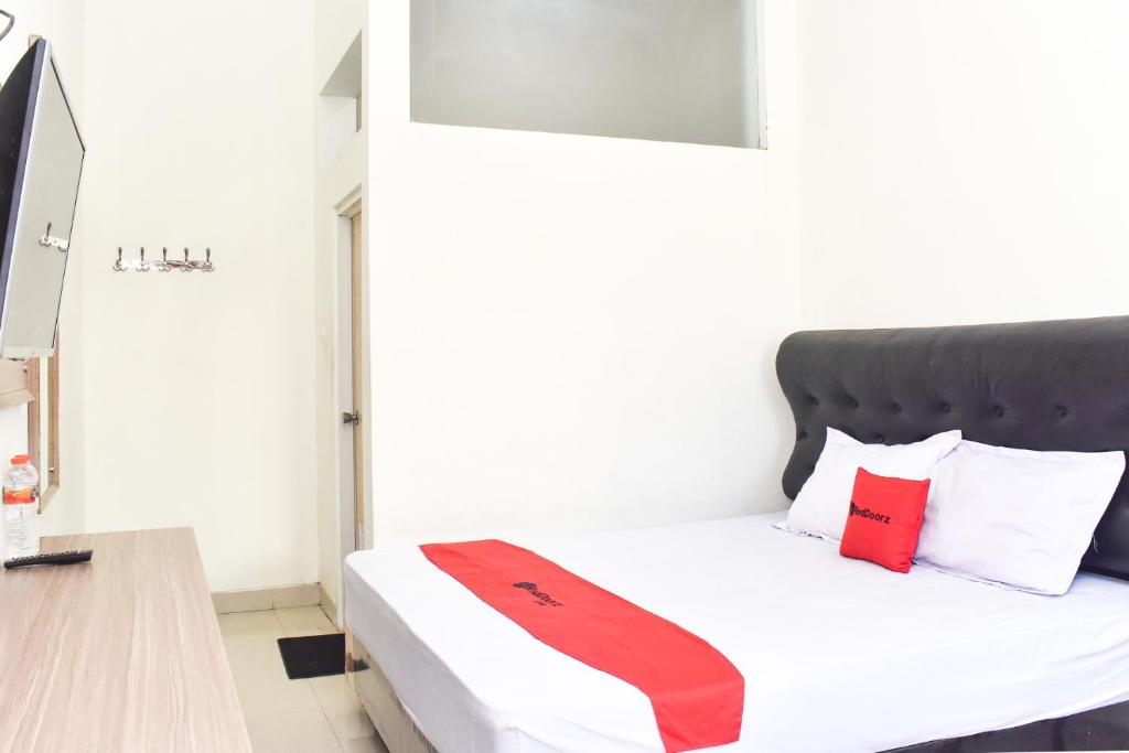 um quarto com uma cama com uma gravata vermelha em RedDoorz near Alun Alun Wonosobo em Wonosobo
