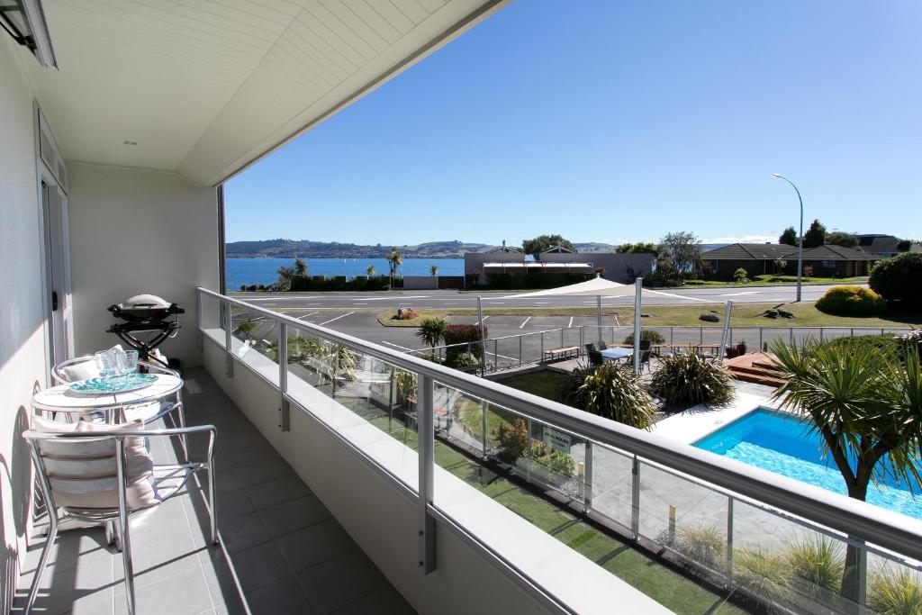 a balcony with a view of the pool and the ocean at Lake Terrace Apartment in Taupo