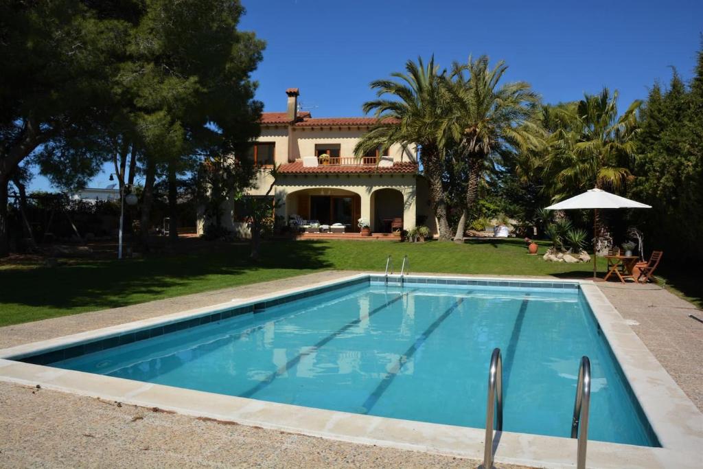 a swimming pool in front of a house at Villa Sitges Colibri at 10 min Walk Beaches - Center City Amaizing Garden Pool XXL Private Tenis Piste in Vilanova i la Geltrú