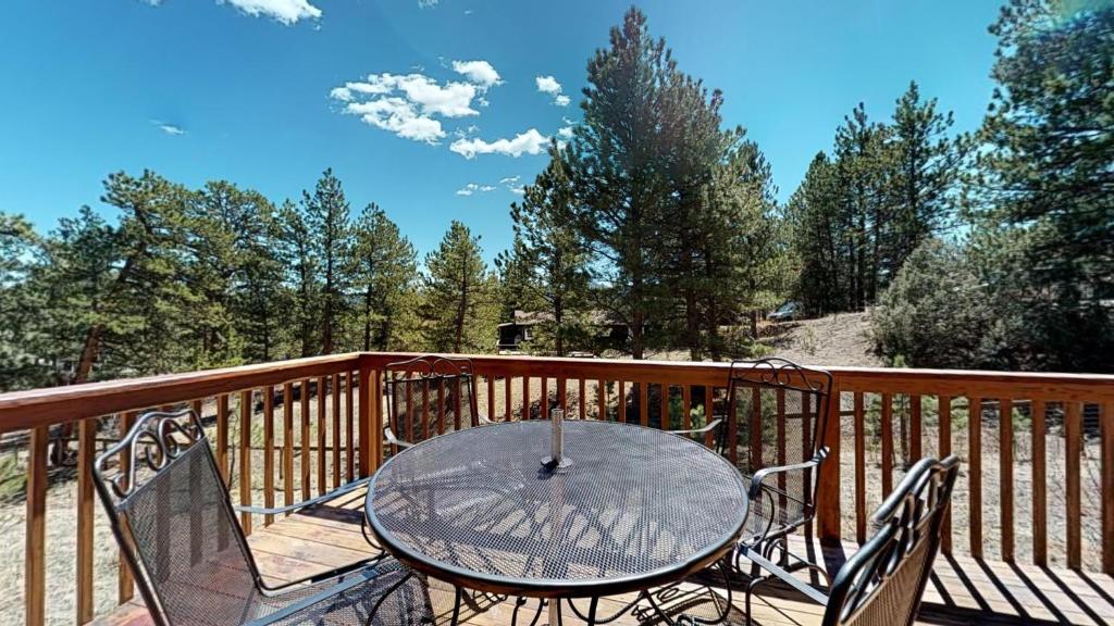 a glass table and chairs on a wooden deck at Whispering Wind in the Trees - Permit #3504 in Estes Park
