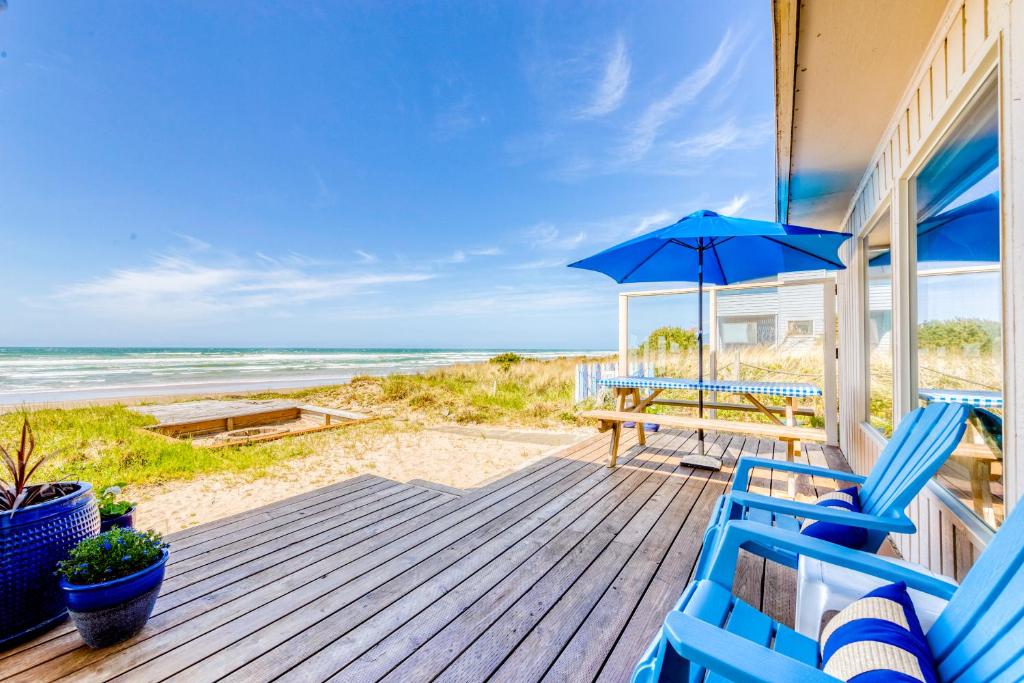 a porch with blue chairs and an umbrella on the beach at 2 Bed 2 Bath Vacation home in Rockaway Beach in Rockaway Beach