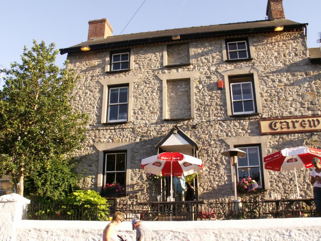 a stone building with two umbrellas in front of it at Carew Inn in Tenby