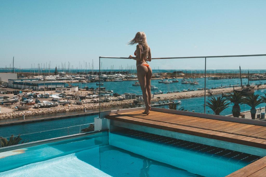 a woman in a bikini standing on top of a swimming pool at Lagos Avenida Hotel in Lagos