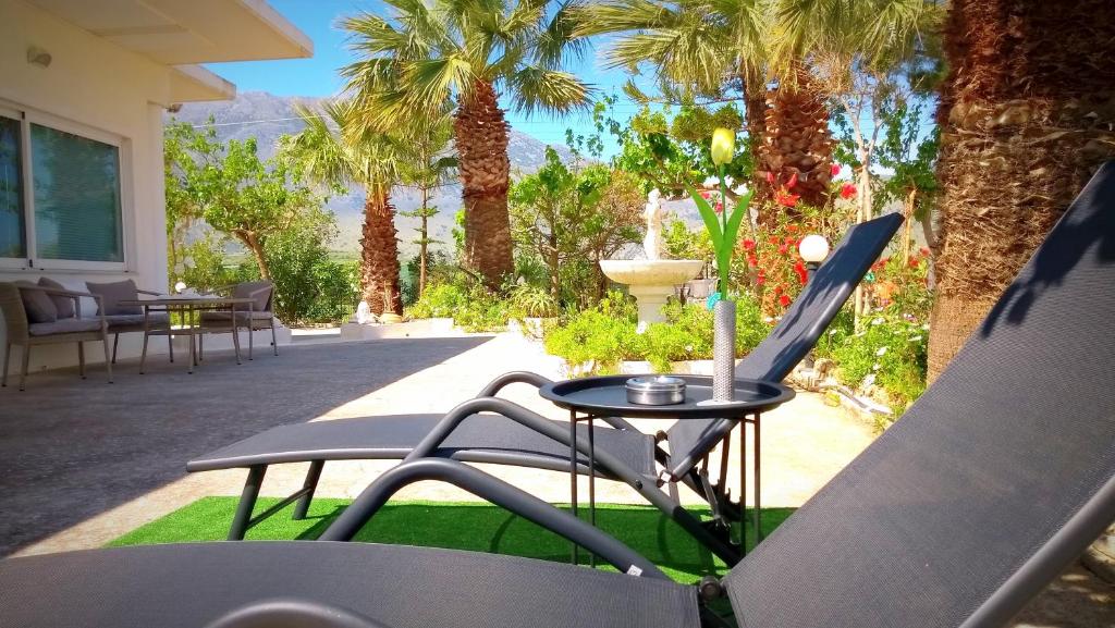 a patio with a table and chairs and palm trees at Christianna House -Villa in Georgioupolis