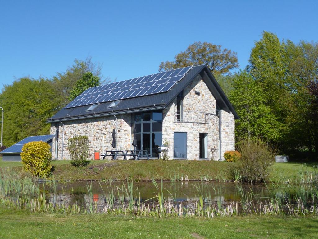 a barn with solar panels on its roof next to a pond at Oxygen House, Holiday and Team building in Ovifat