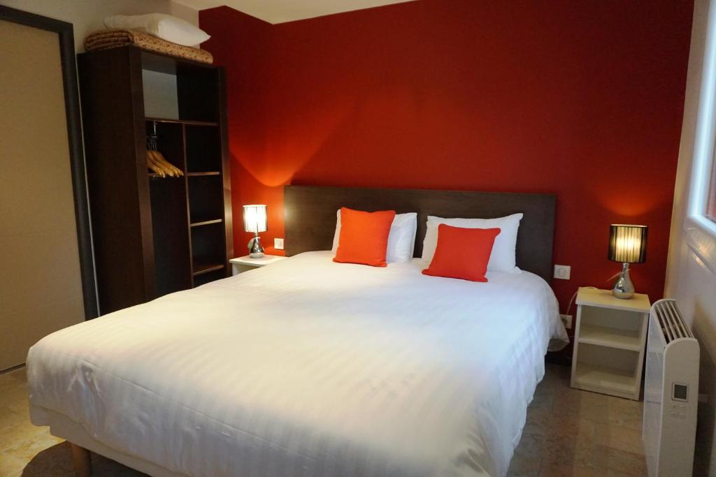 ディジョンにあるオテル レストラン デュ パルク ドゥ ラ コロンビエールのベッドルーム1室(赤い壁の白い大型ベッド1台付)