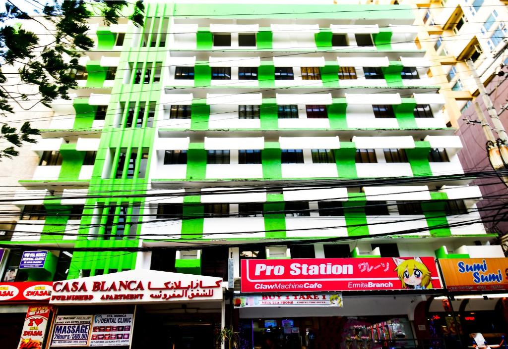 a tall green and white building with signs in front of it at Casa Blanca Apartment in Manila