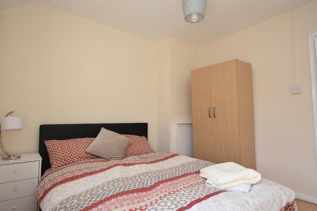 a bedroom with a bed and a wooden cabinet at London Deluxe Four Bedroom House in Dagenham
