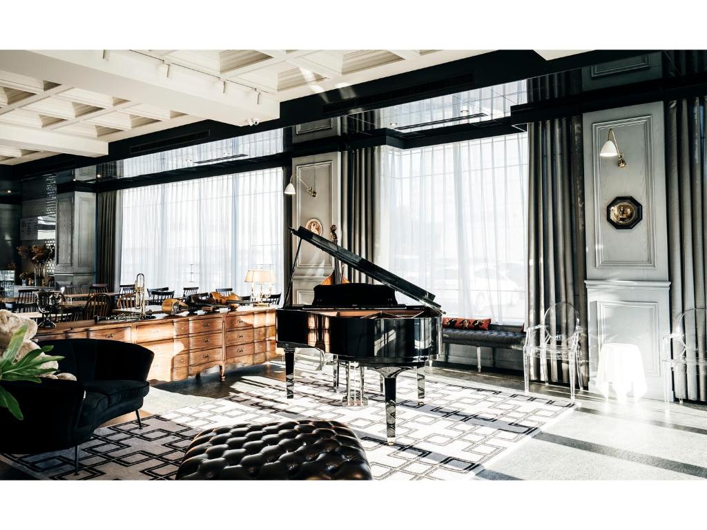 a room with a piano in a room with windows at Hôtel de Ľeau in Anping