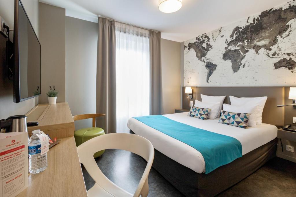 
a hotel room with a bed, desk, chair, and a lamp at Appart’City Confort Le Bourget - Aéroport in Le Bourget
