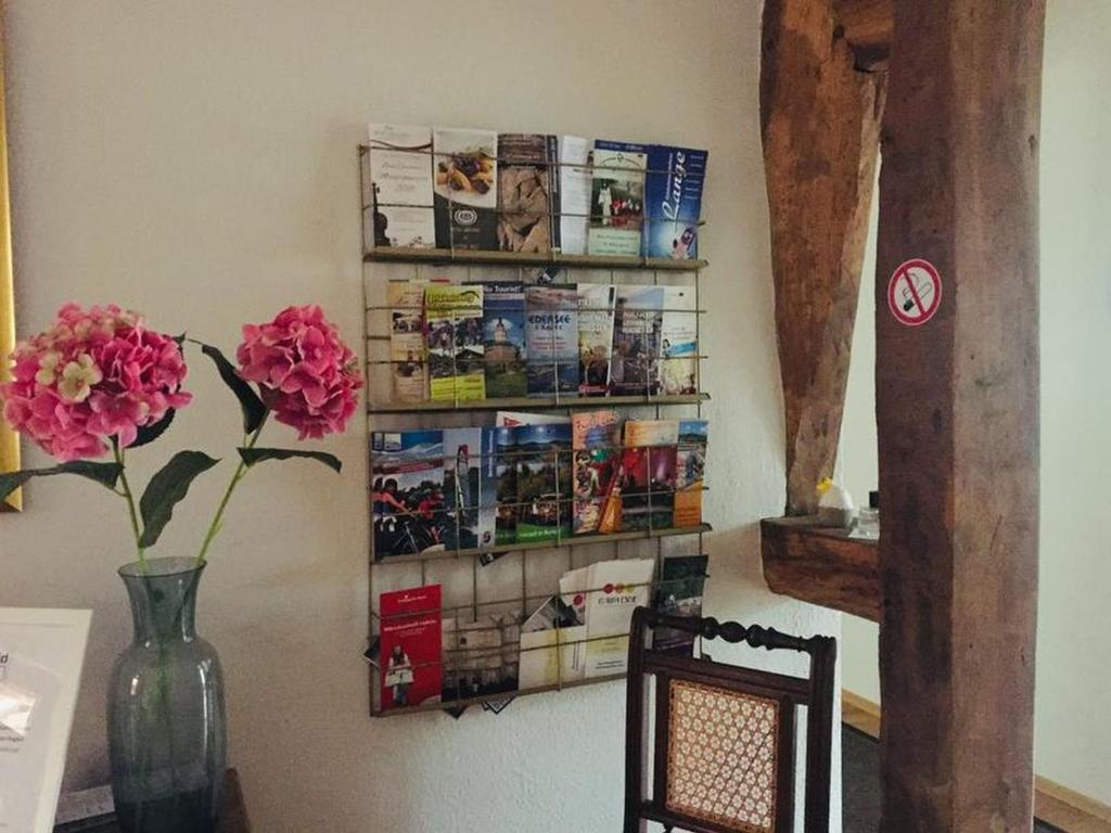 a table with a vase with flowers and magazines on a wall at Posthof Kerstenhausen in Borken