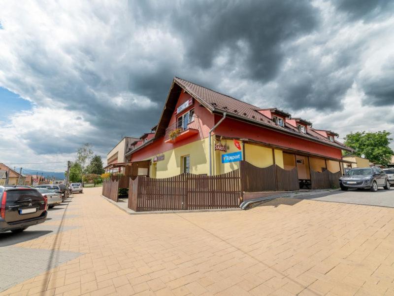Penzión & Bar NATALI في Spišský Štvrtok: مبنى على جانب شارع فيه سيارات متوقفة