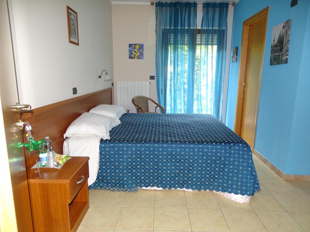 1 dormitorio con 1 cama con colcha azul y blanca en Villa Biancofiore, en San Giovanni Rotondo