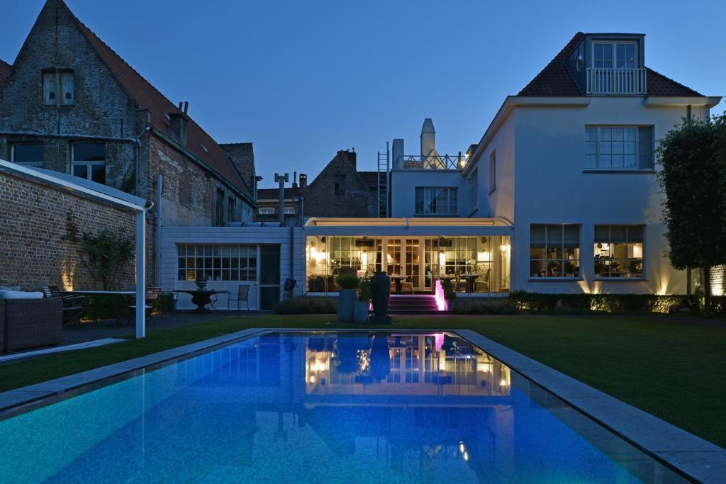 une maison avec une piscine en face d'un bâtiment dans l'établissement Casa Romantico, à Bruges