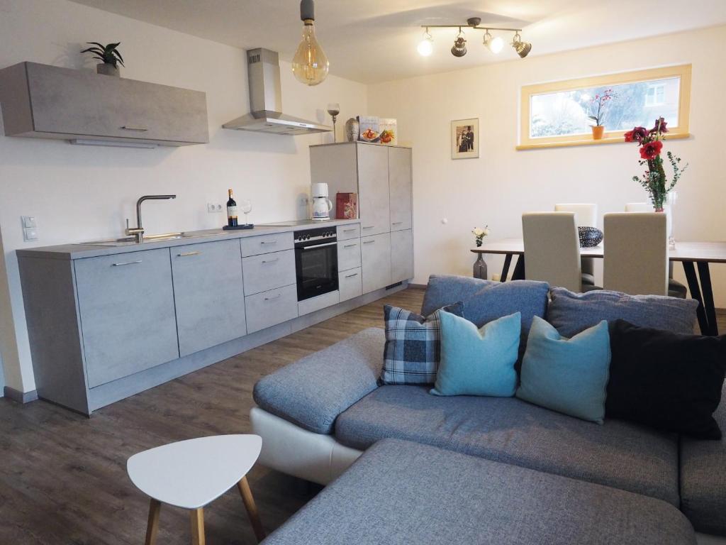 uma sala de estar com um sofá azul e uma cozinha em Apartment Silbertal - Ferienwohnung em Silbertal