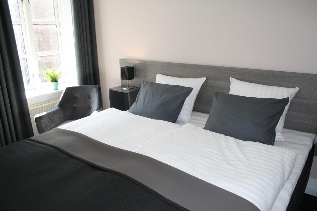 a large white bed with two pillows and a window at Hotel Aarhus City Apartments in Aarhus