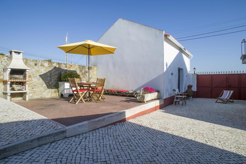 a patio with a table and an umbrella at Casas do Bárrio in Alcobaça