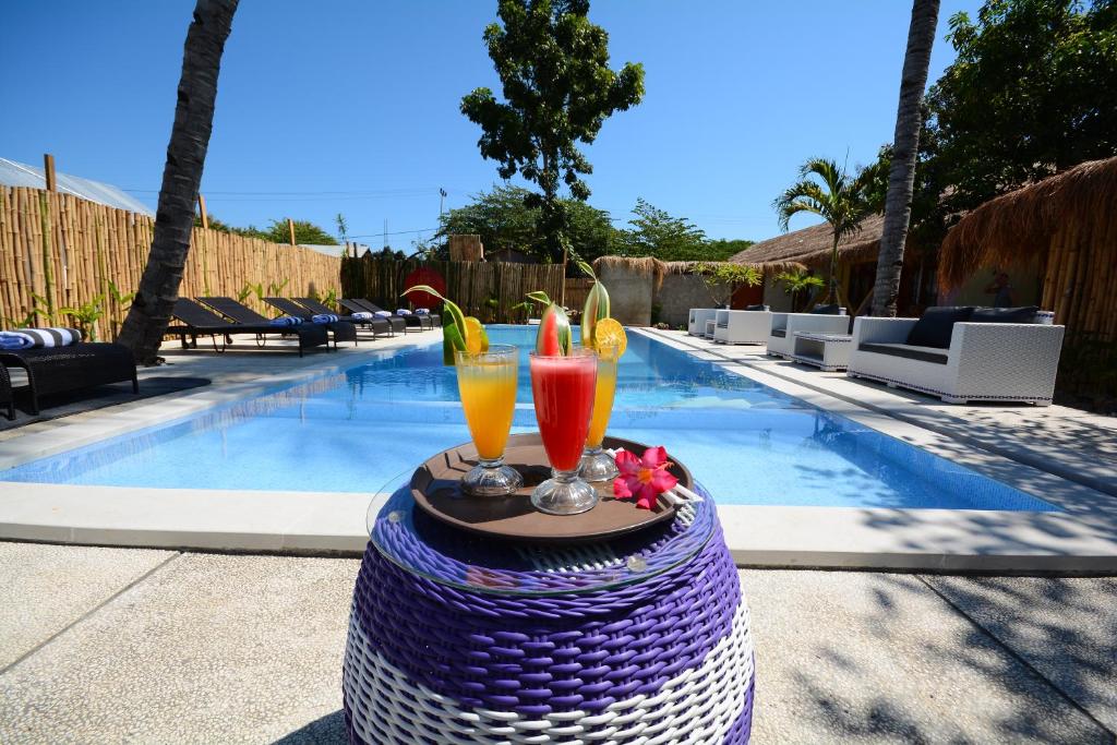 two drinks on a table next to a swimming pool at World BnB in Labuan Bajo