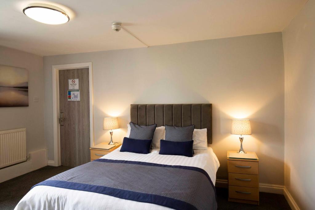 a bedroom with a large bed with blue pillows at The Kinderton in Middlewich