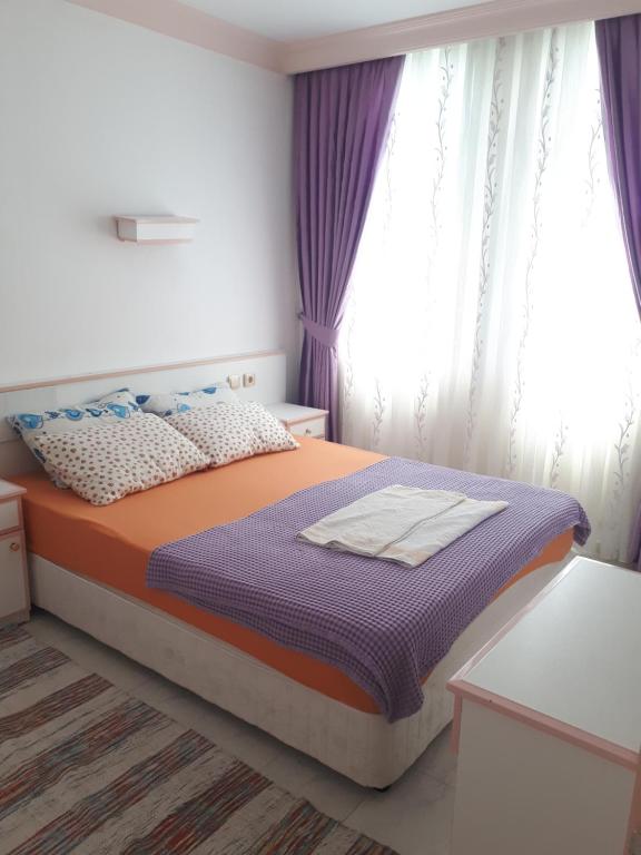 a bedroom with a bed with purple curtains at Aygun Apart Daire in Mahmutlar
