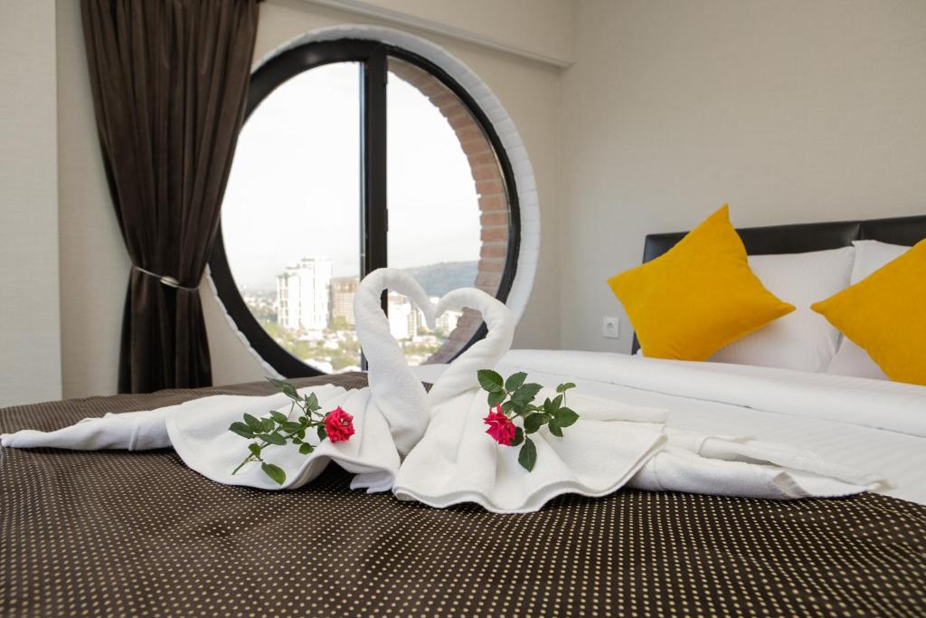 zwei Schwäne Handtücher auf einem Bett vor einem Fenster in der Unterkunft Boutique Hotel in Tbilisi City
