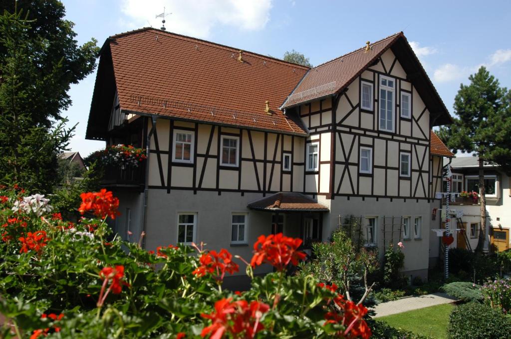 ein Haus mit roten Blumen davor in der Unterkunft Pension Lindenhof in Kromsdorf