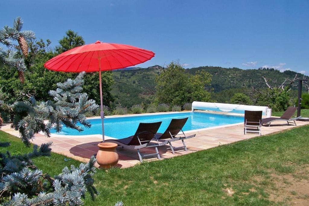 a red umbrella sitting next to a swimming pool at Mas de Bouilhac in Pranles