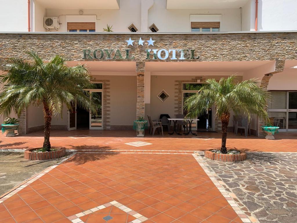 a hotel with two palm trees in front of a building at Hotel Royal in Coccorino